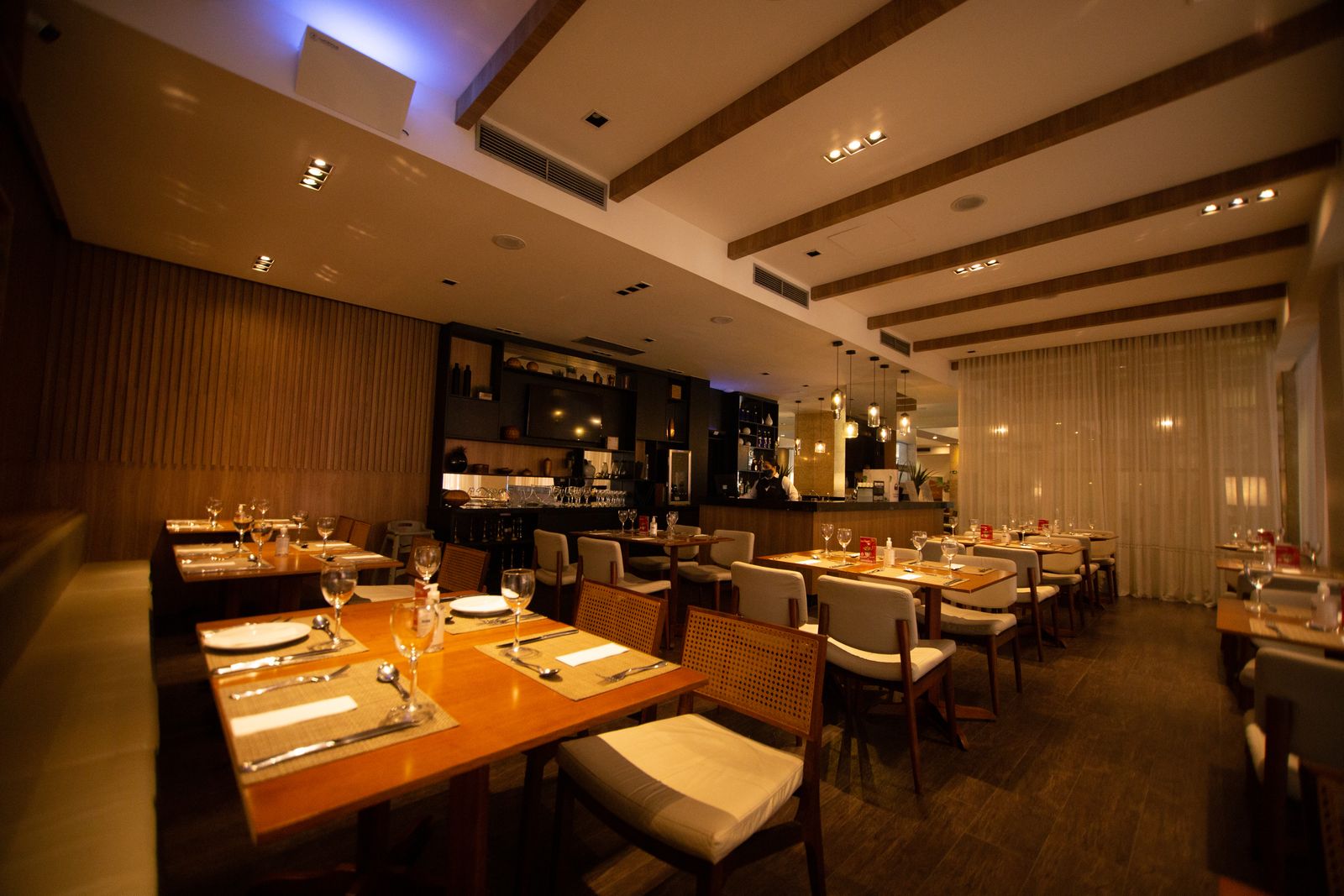 A warm restaurant dining room with a mix of two-tops, four-tops, and a banquette, the table layout a restaurant floor plan has to get right